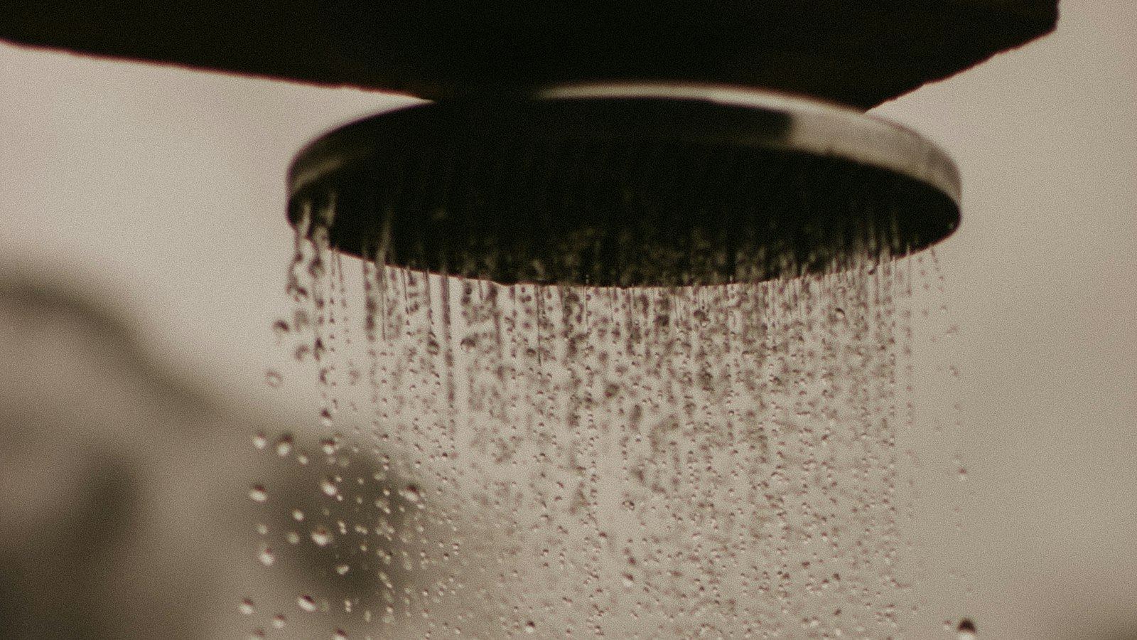 Water falling from a rain shower head in warm low light